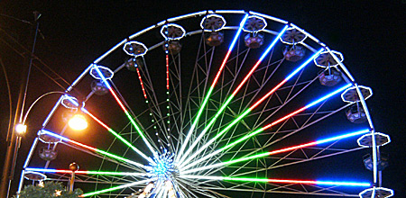 Auf diesem Bild sieht man ein bunt beleuchtetes Riesenrad.