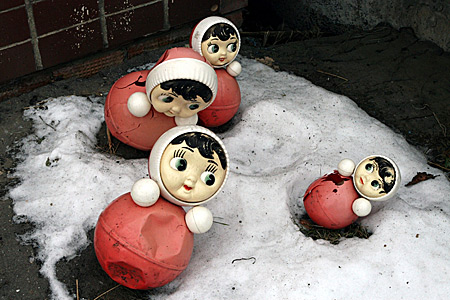 Auf diesem Bild sieht man vier von diesen russischen Puppen im Schnee liegen.