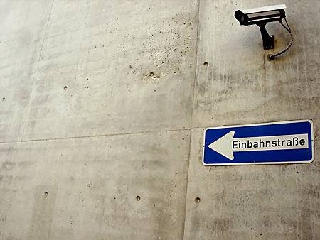 Auf diesem Bild sieht man eine Überwachungskamera und darunter ein Einbahnstraßen-Schild.